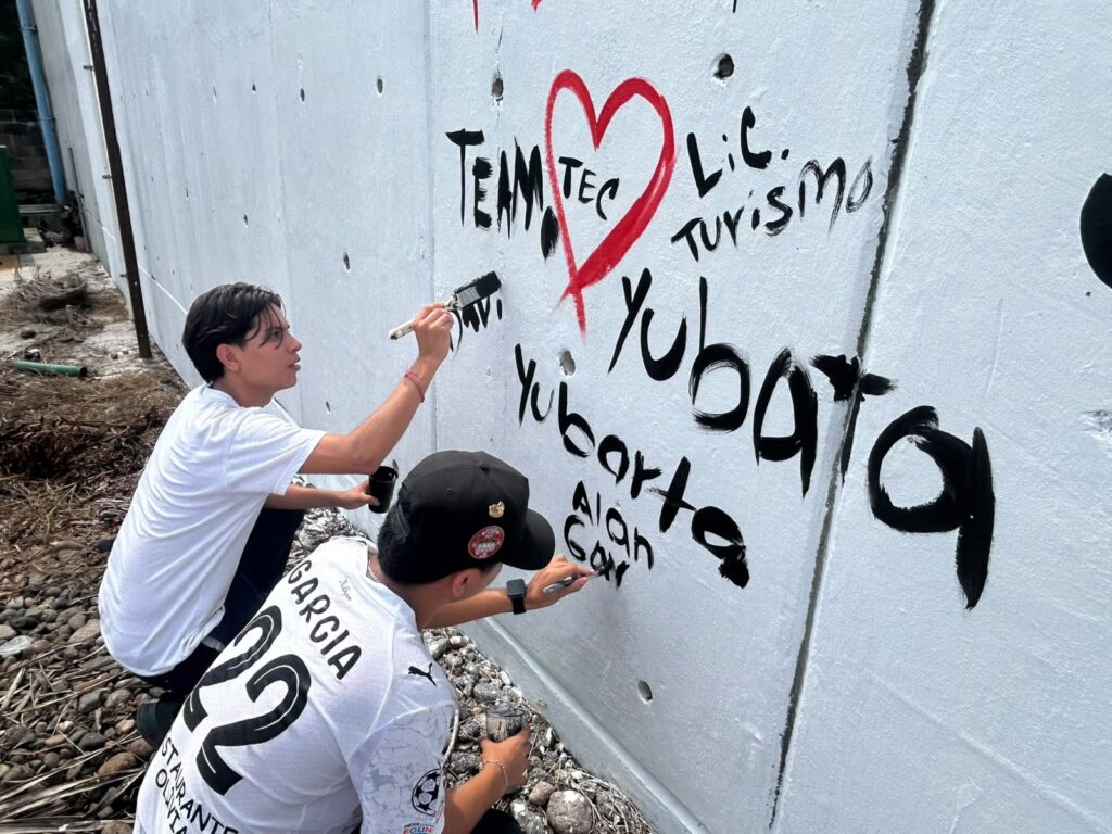 dos estudiantes pintando el mural