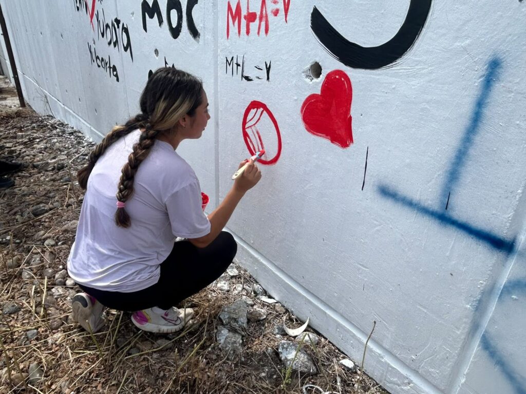una estudiante en la pinta del mural