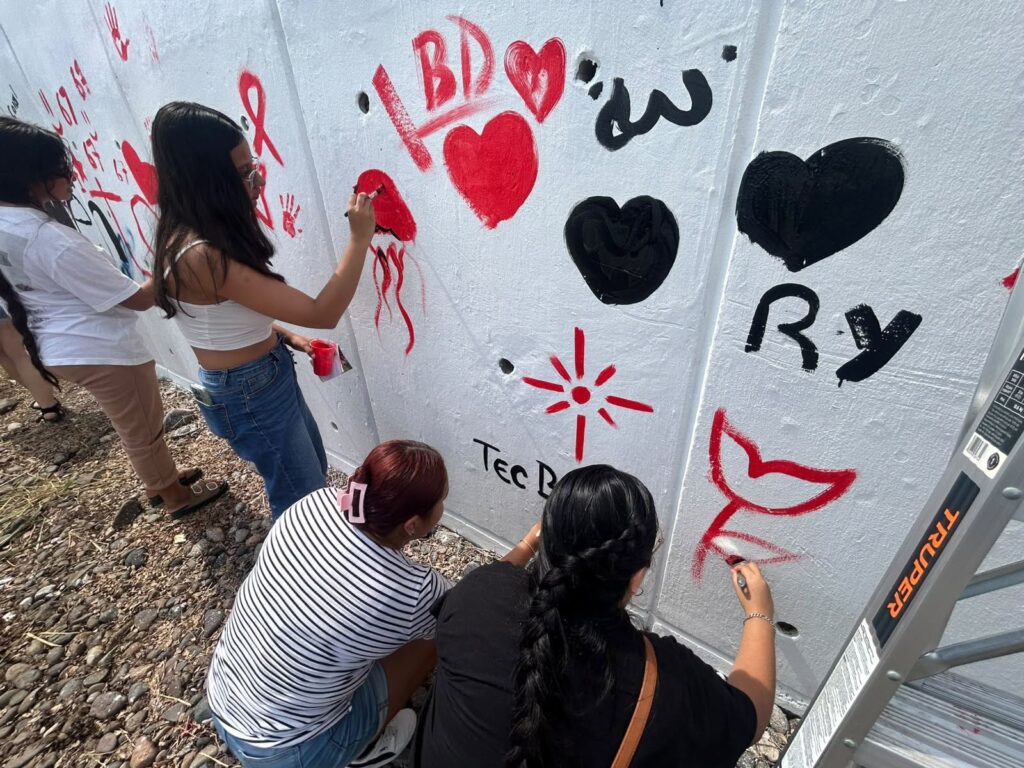 cuatro estudiantes en la pinta del mural