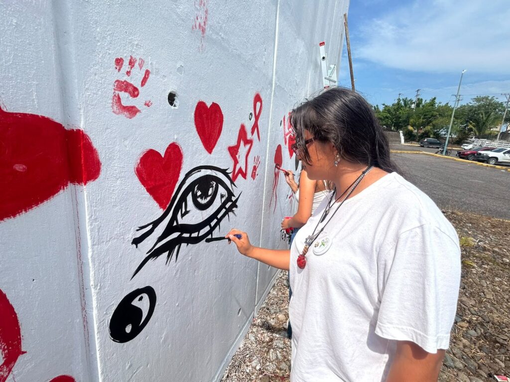 estudiante pinta un ojo en el mural