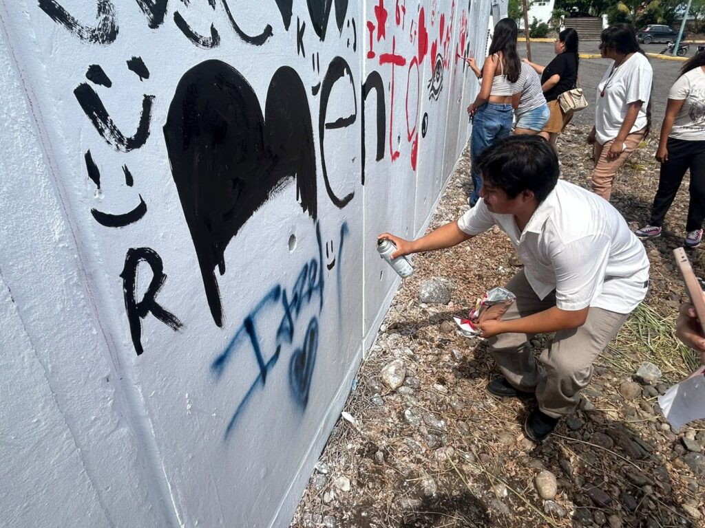 estudiante pinta el mural con aerosol