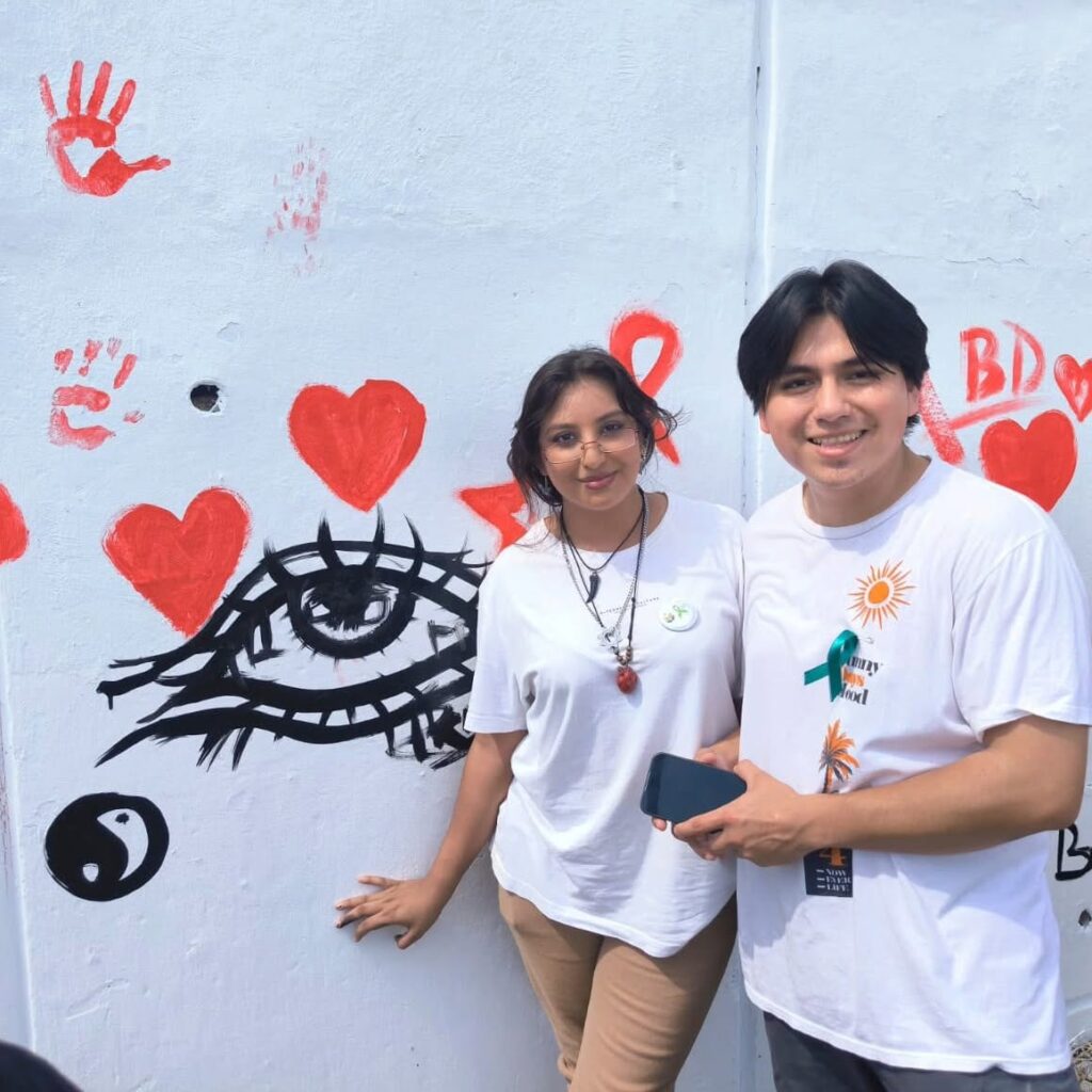 dos estudiantes posan en el mural